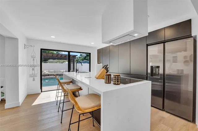 a kitchen with stainless steel appliances granite countertop a dining table chairs and refrigerator