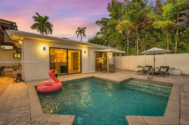 a view of a backyard with furniture and a table and chair under an umbrella