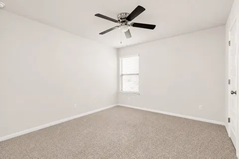 an empty room with a window and a ceiling fan