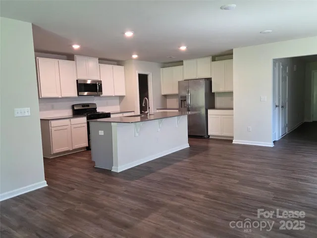 a kitchen with stainless steel appliances granite countertop a stove top oven a refrigerator a sink and a oven