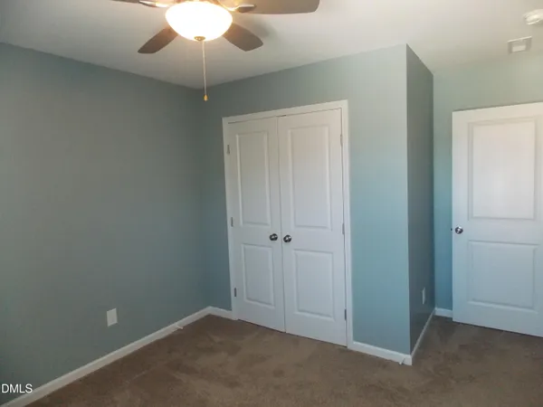 a view of an empty room with a chandelier fan