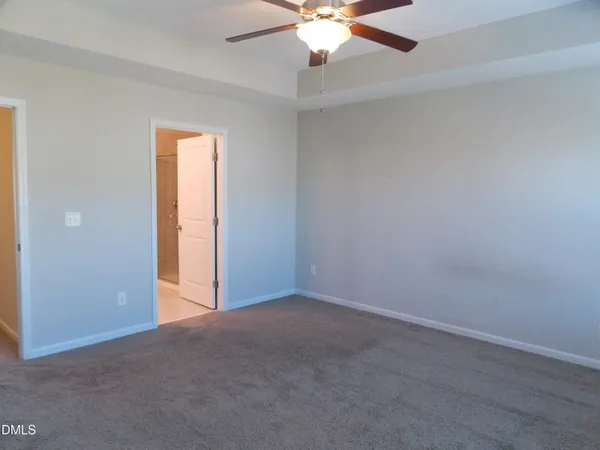 an empty room with a chandelier fan and windows