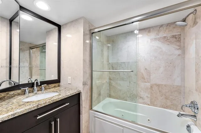 a bathroom with a granite countertop bathtub shower sink and mirror