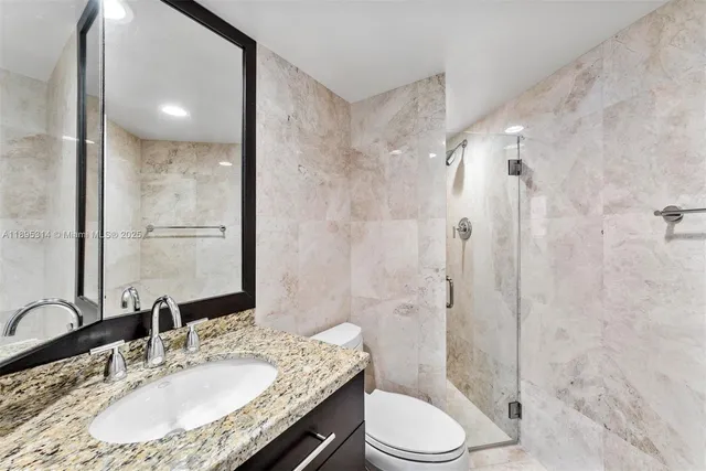 a bathroom with a granite countertop sink toilet a mirror and shower