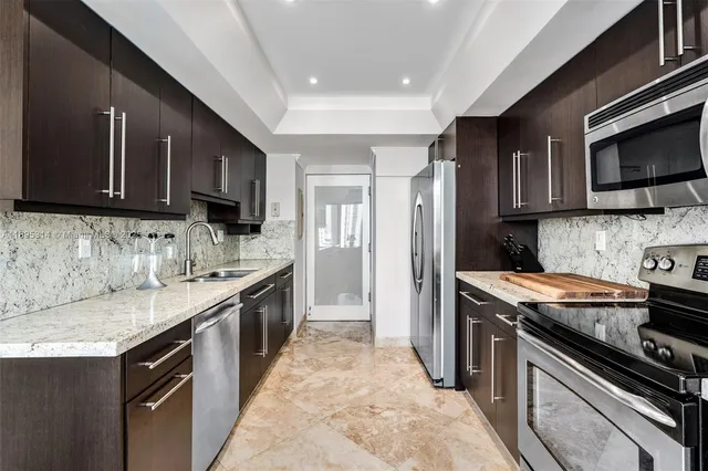 a kitchen with stainless steel appliances granite countertop a stove top oven a sink dishwasher and a refrigerator with wooden cabinets