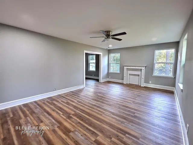 a view of empty room with wooden floor and fireplace