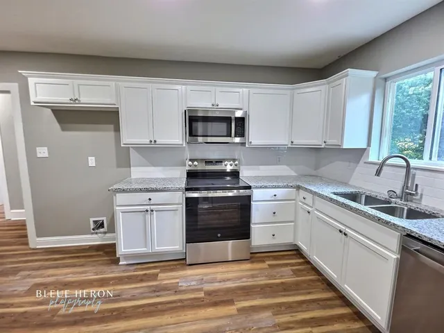 a kitchen with white cabinets and appliances