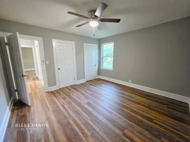an empty room with wooden floor and a ceiling fan
