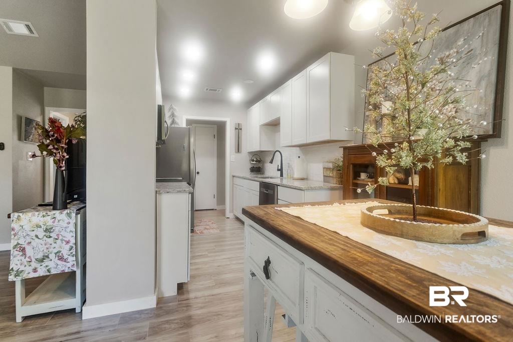 601 East Gate Circle Foley, AL 36535 - Photo 17 of 26 Kitchen featuring stainless steel appliances, light hardwood / wood-style floors, sink, white cabinets, and wood counters