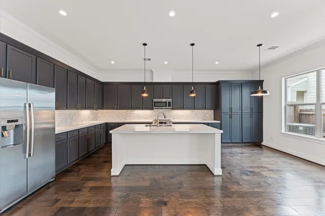 a large white kitchen with a large counter top a sink stainless steel appliances and cabinets