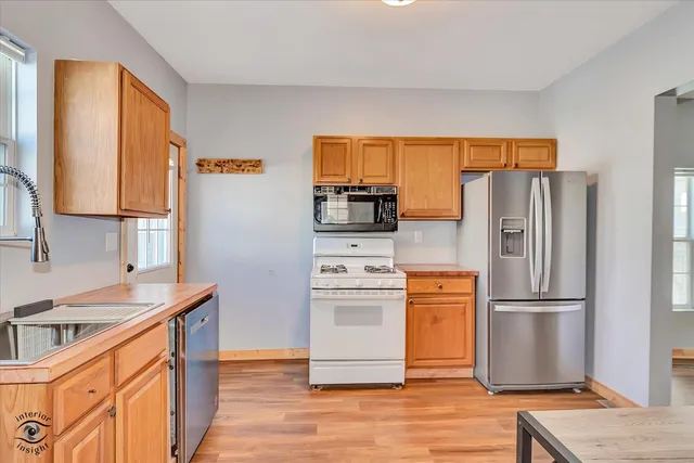 a kitchen with stainless steel appliances granite countertop a refrigerator a stove and a sink with wooden floors