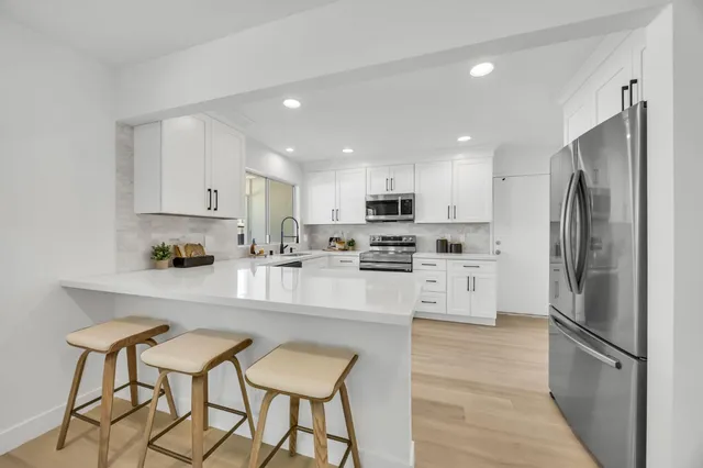 a view of a hallway with wooden floor and a bathroom