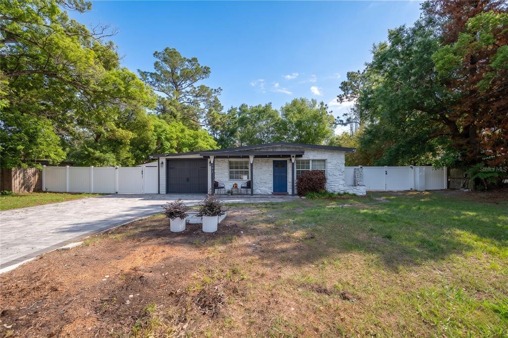 a backyard of a house with table and chairs plants and large tree