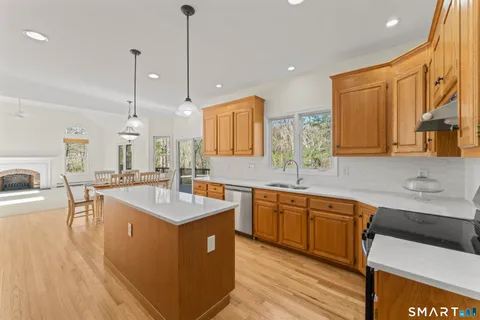 a kitchen with stainless steel appliances granite countertop a sink a stove and a wooden floors