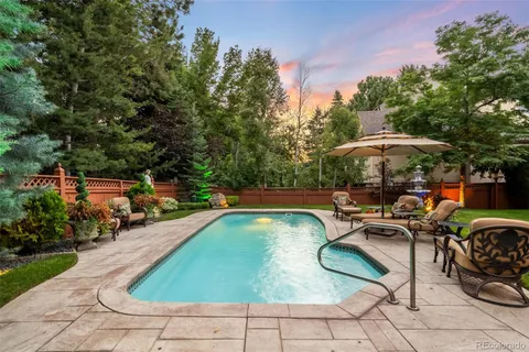 a view of swimming pool with outdoor seating and trees in the background