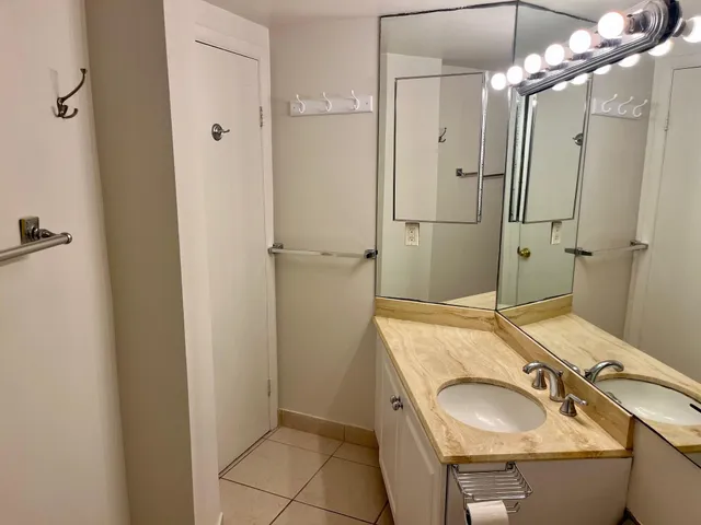 a bathroom with a sink double vanity granite tub shower and mirror