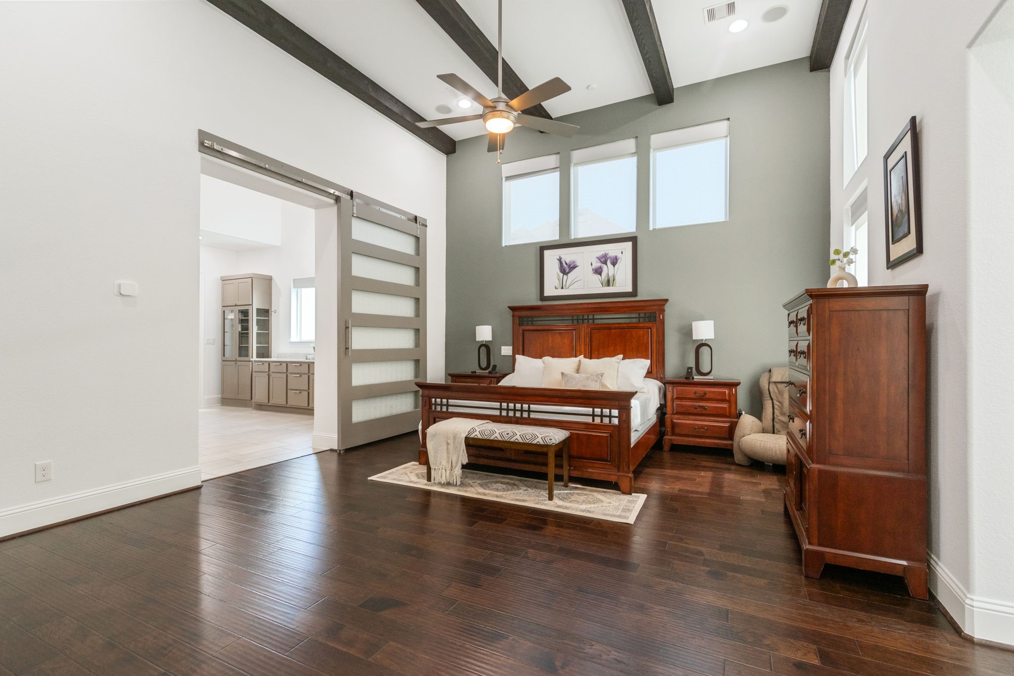 28518 Hoffman Spring Lane Fulshear, TX 77441 - Photo 19 of 50 The downstairs primary retreat is exceptional with high ceilings with wood beams, ceiling fan and ensuite bathroom.