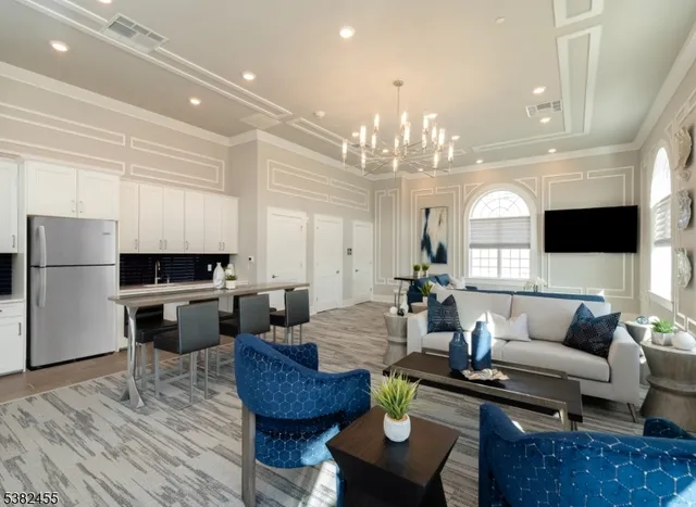 a living room with furniture kitchen view and a chandelier