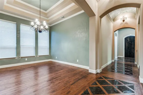 an empty room with wooden floor chandelier and windows