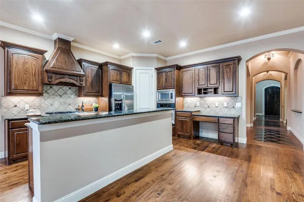 a kitchen with kitchen island granite countertop wooden floors a stove and white stainless steel appliances