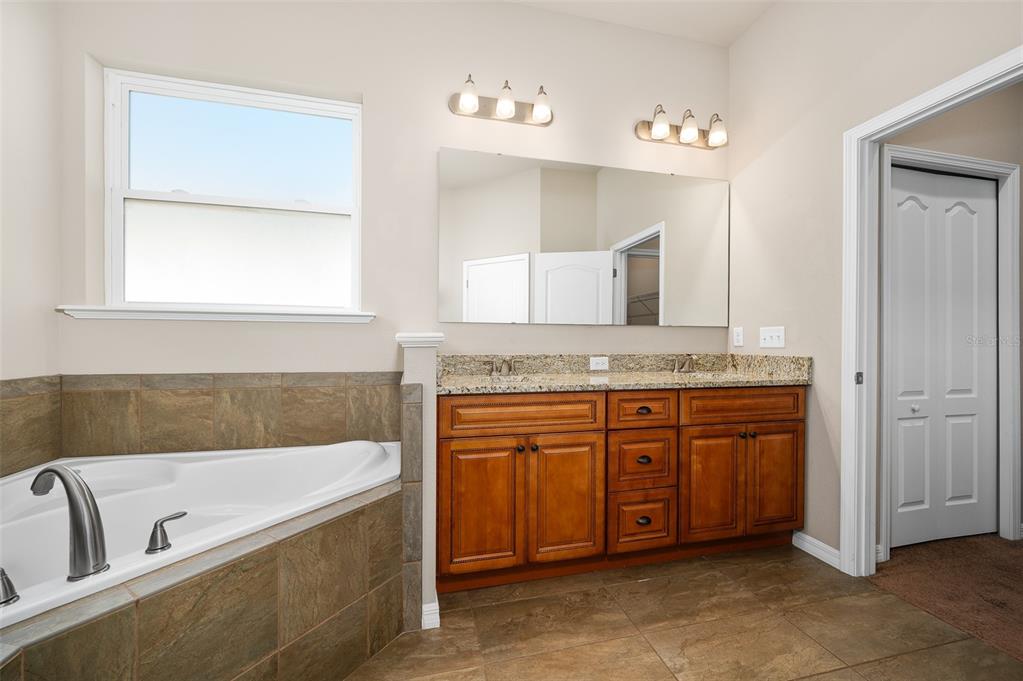 2779 Southwest 121st Drive Gainesville, FL 32608 - Photo 21 of 39 a bathroom with a granite countertop tub sink and mirror