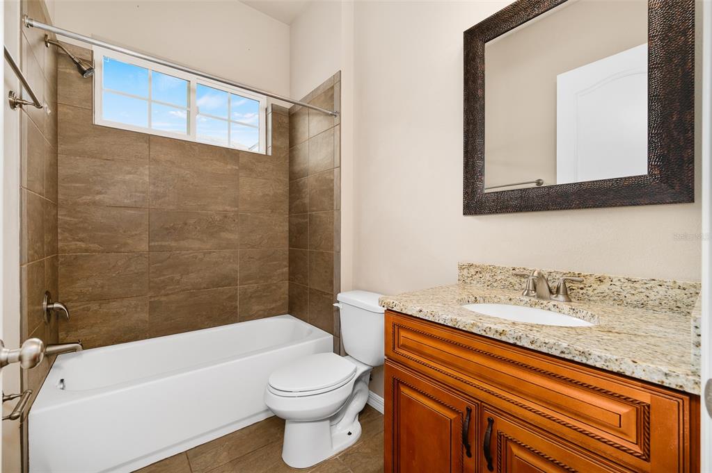 2779 Southwest 121st Drive Gainesville, FL 32608 - Photo 27 of 39 a bathroom with a granite countertop bathtub sink vanity mirror and toilet