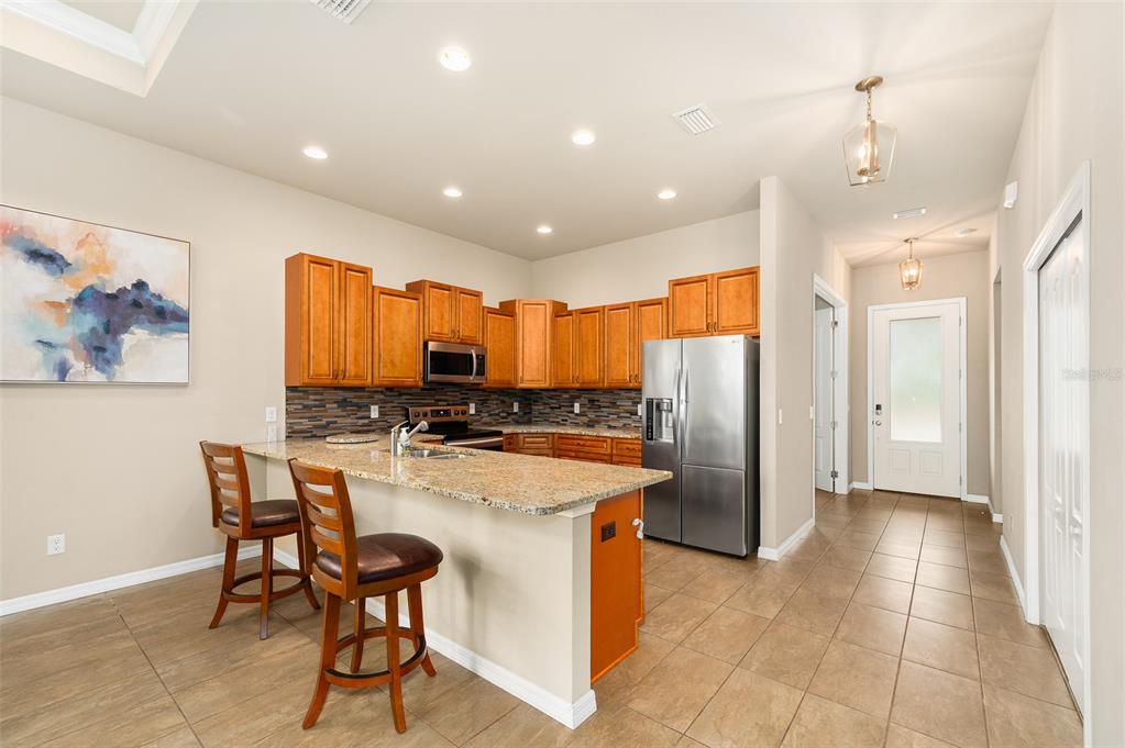 2779 Southwest 121st Drive Gainesville, FL 32608 - Photo 8 of 39 a kitchen with stainless steel appliances granite countertop a refrigerator a stove a sink a oven with a dining table and chairs