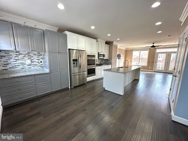 a living room with stainless steel appliances kitchen island wooden floors wooden cabinets and entryway