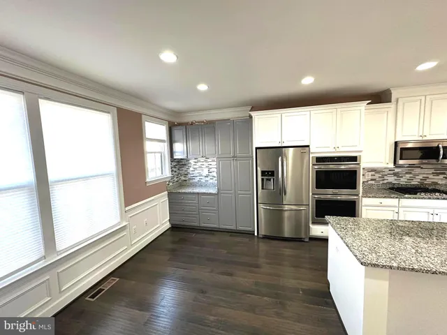 a kitchen with granite countertop a refrigerator and wooden cabinets