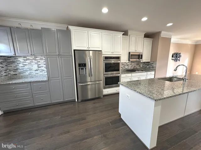 a kitchen with kitchen island granite countertop stainless steel appliances and wooden cabinets
