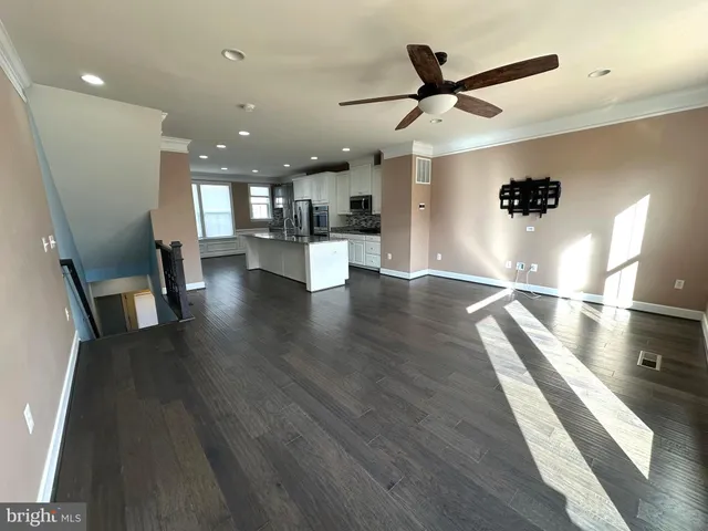 a view of a living room with wooden floor and a ceiling fan