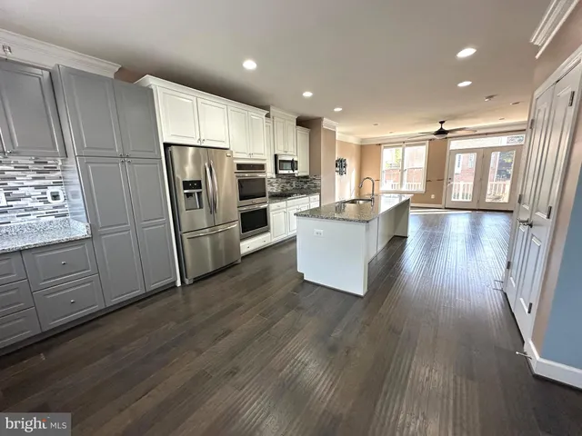 a kitchen with kitchen island wooden floors appliances and cabinets
