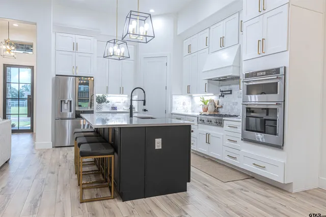 a kitchen with kitchen island granite countertop a sink cabinets and stainless steel appliances