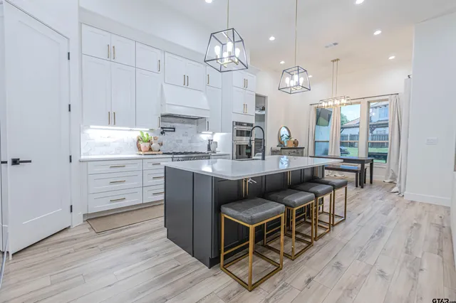 a kitchen with granite countertop a stove a sink a dining table and chairs