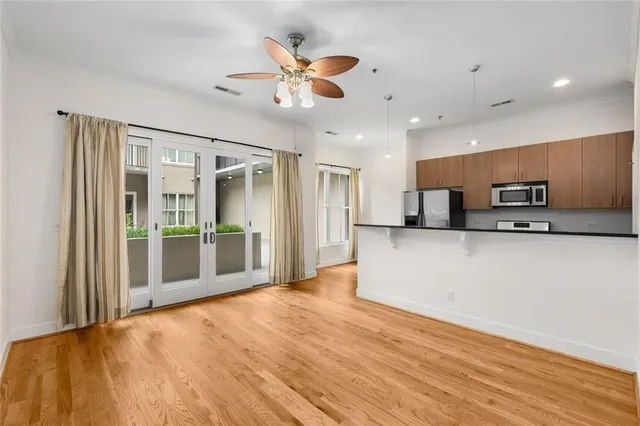 a view of an empty room with wooden floor and a ceiling fan