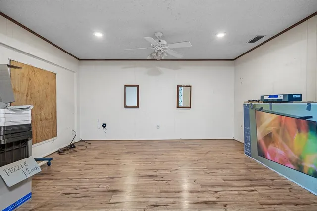 a view of an empty room with wooden floor and kitchen