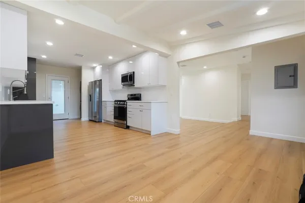 a view of kitchen with stainless steel appliances kitchen island wooden floor and living room view