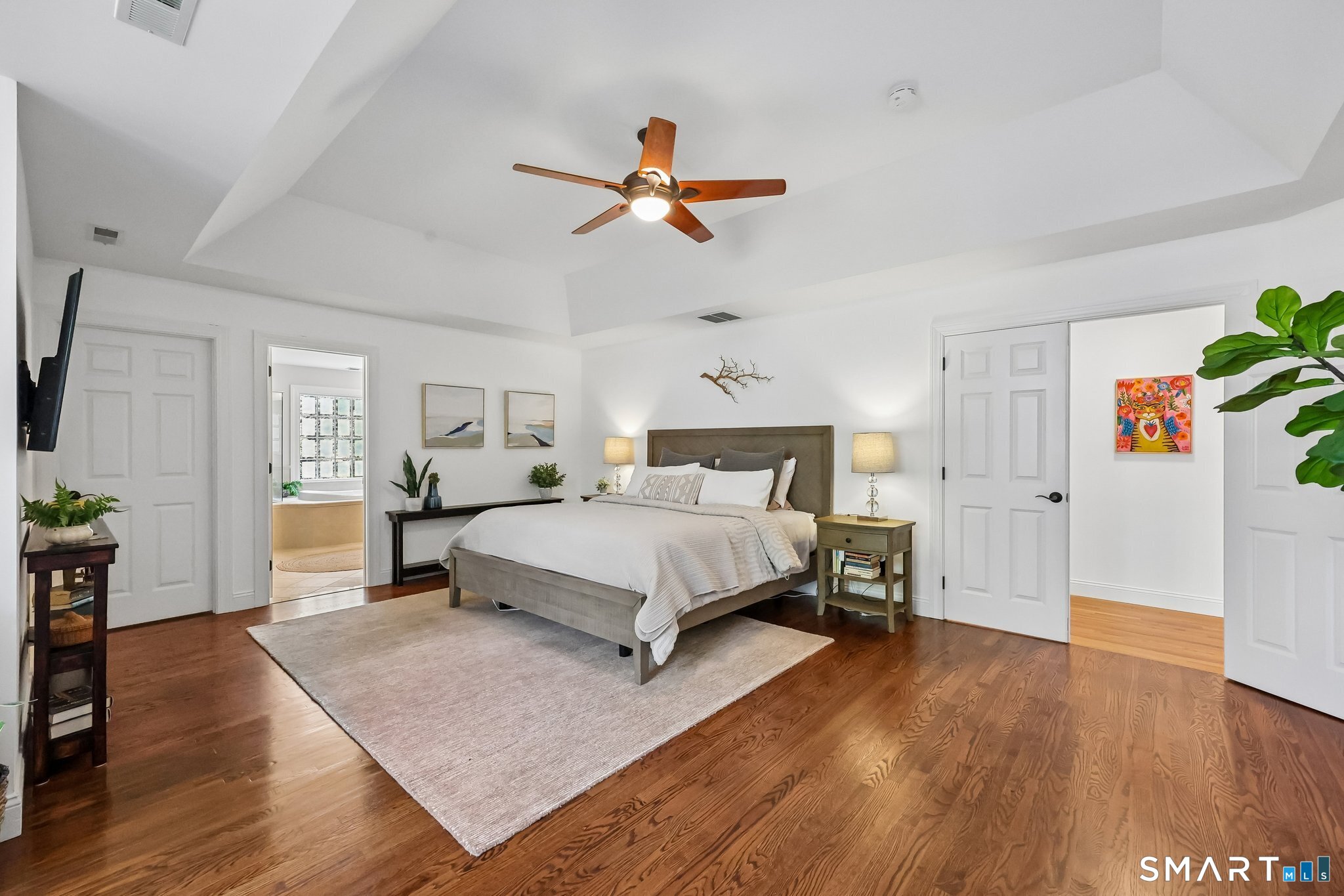 3 East Lake Road Danbury, CT 06811 - Photo 20 of 37 The expansive primary bedroom suite is enhanced by a refined tray ceiling and rich hardwood floors, creating a warm and sophisticated retreat.