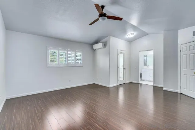 an empty room with wooden floor and ceiling fan