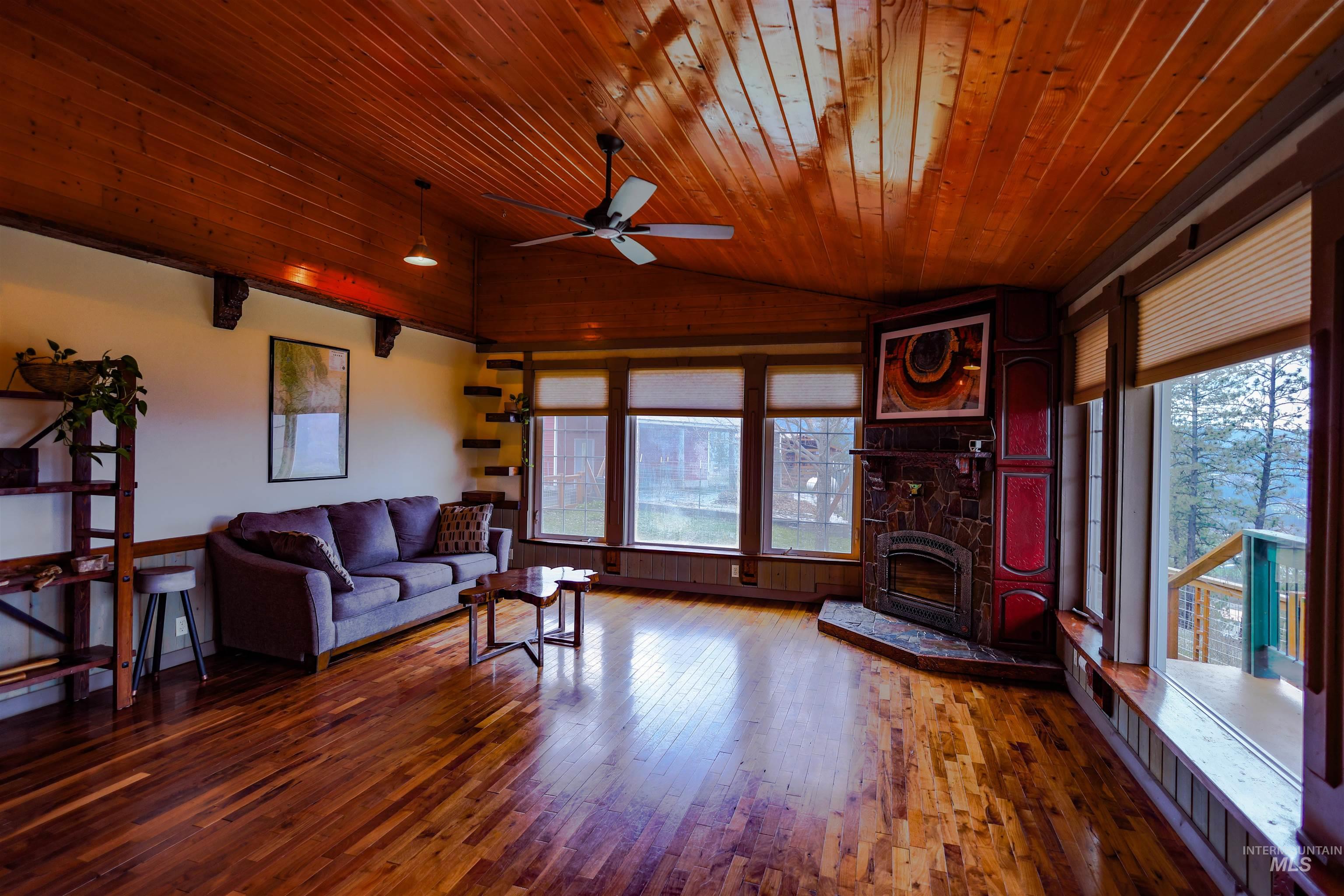 402 Beaverslide Road Kamiah, ID 83536 - Photo 16 of 46 Living room with a ceiling fan, dark wood finished floors, a fireplace, and a vaulted wooden ceiling