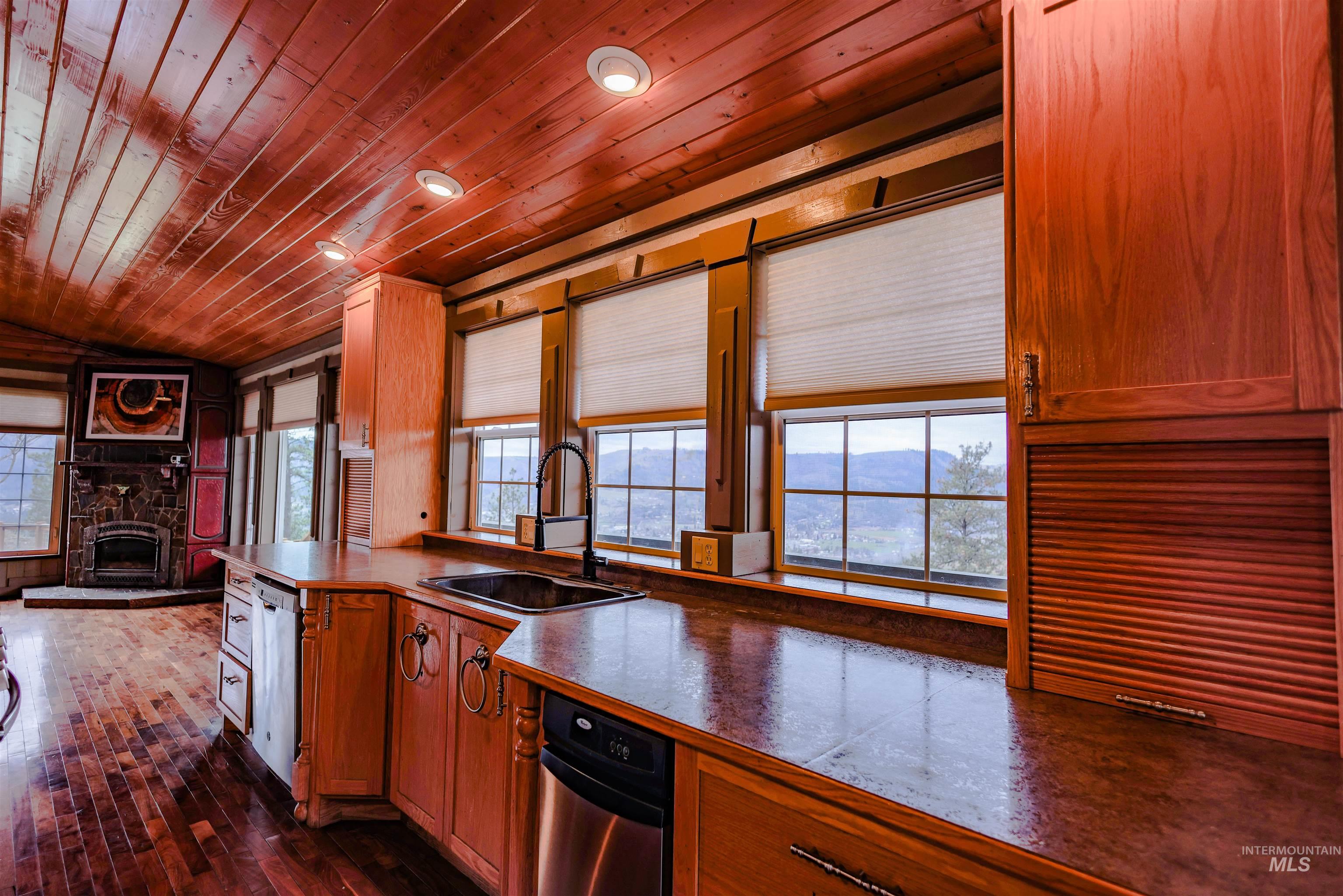 402 Beaverslide Road Kamiah, ID 83536 - Photo 20 of 46 Kitchen featuring a vaulted wooden ceiling, wood finish cabinets, a stone fireplace, dark wood-style flooring, and recessed lighting