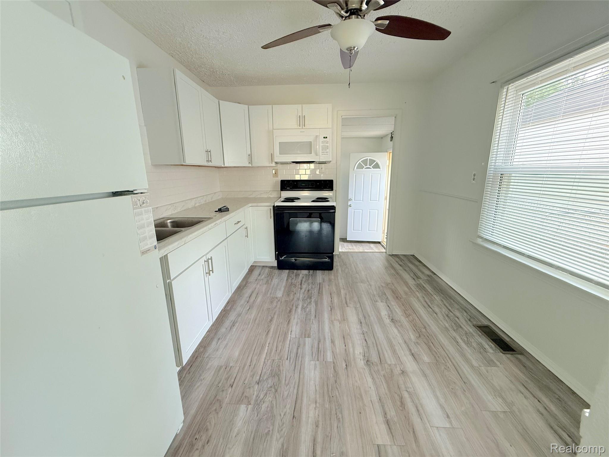 21212 Rensselaer Street Farmington, MI 48336 - Photo 4 of 11 Kitchen featuring wood-finish flooring, white cabinetry, and light countertops