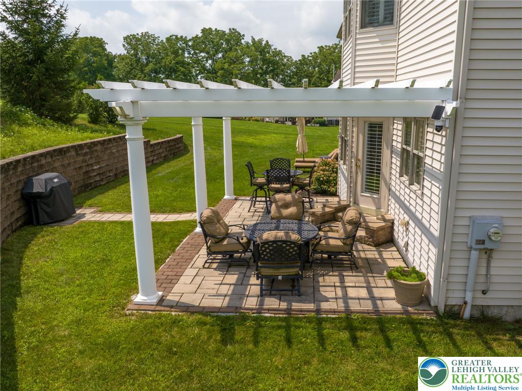 217 Gower Road Nazareth, PA 18064 - Photo 6 of 44 An inviting paver patio extends from the home, offering shaded outdoor living under a charming white pergola.