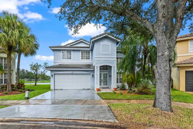a front view of a house with a garden and trees