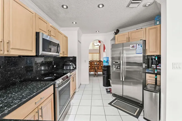 a kitchen with stainless steel appliances granite countertop a refrigerator a stove and a sink