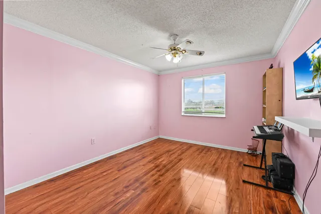 a view of empty room with wooden floor and fan