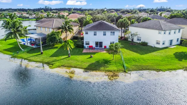 a view of a white house with a yard and table and chairs under an umbrella