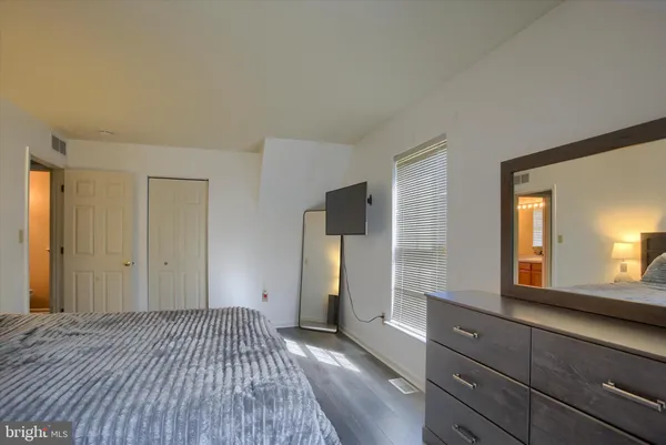 a bedroom with a bed and a large mirror on dresser