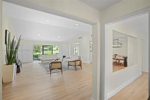 a living room with furniture a large window and wooden floor