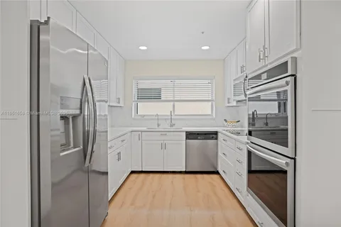 a kitchen with granite countertop cabinets appliances and a counter space